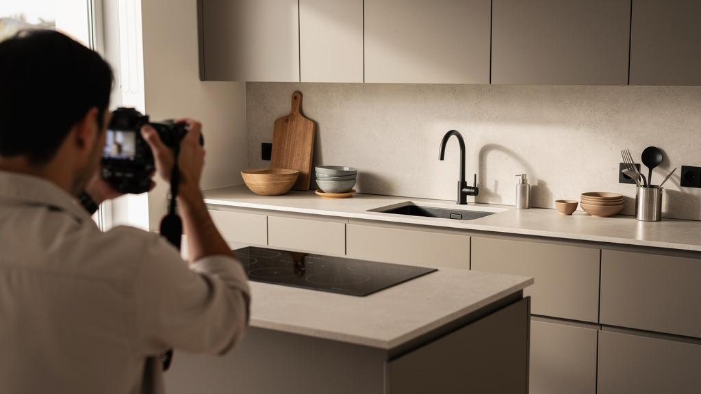 Photographe cadrant une cuisine moderne avec un appareil reflex