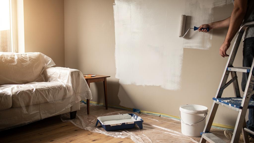 Propriétaire peignant un mur en blanc cassé